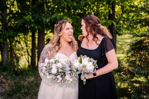 Two people sharing joyful moment with bouquets in sunny outdoor setting.