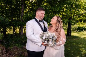 A candid wedding moment captured in a garden with soft natural light filtering through trees.