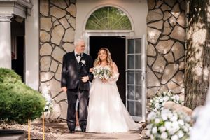 Stone archway entrance decorated with delicate white flowers for wedding ceremony.