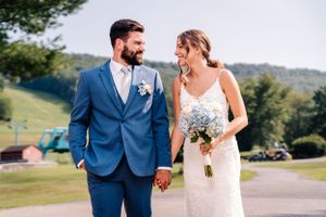 A couple in wedding attire shares a tender moment against a mountainous backdrop.