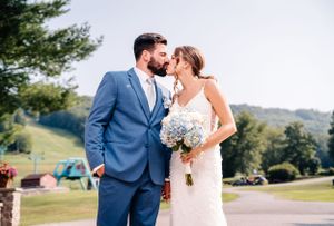 A romantic wedding portrait with blue sky and mountain scenery in the background.
