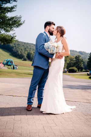 A loving moment captured between newlyweds on a paved outdoor pathway.