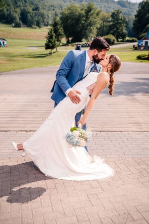 A romantic dip pose between newlyweds on their wedding day with mountains in the background.