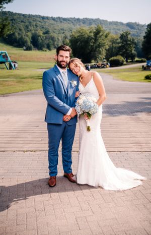 A sweet wedding portrait on a paved pathway with rolling hills and trees in the background.