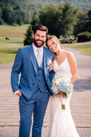 Happy couple embraces during outdoor wedding photoshoot with scenic mountain backdrop.
