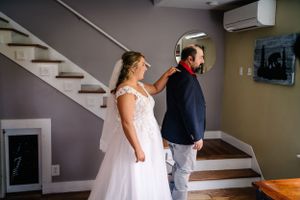 First look wedding moment on staircase with natural light streaming through windows.