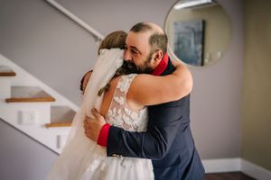 Emotional embrace captured during intimate wedding moment on staircase.