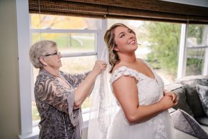 Tender moment of wedding dress preparation by natural window light.