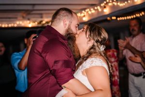 Couple sharing their first dance at rustic wedding reception with string lights overhead.