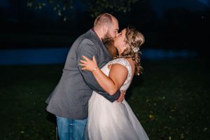 A romantic evening moment between a couple in formal attire outdoors.