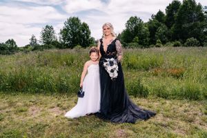 A touching portrait of two people in contrasting black and white dresses standing together in a grassy field.