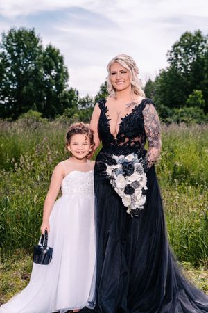 A heartwarming moment captured in a wildflower meadow with two people in elegant formal attire.