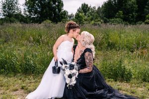 An intimate moment between two people in contrasting formal dresses captured in a natural outdoor setting.