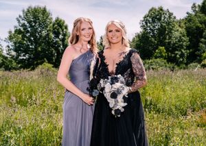 A sunny outdoor portrait of two people in contrasting formal wear standing in a wild meadow.