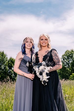 A sunny outdoor portrait featuring two women in formal dresses holding white bouquets.