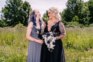 Two figures share a joyful moment in formal wear against a natural outdoor backdrop.