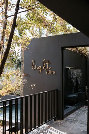 Elegant dark exterior of Light Suite venue with gold signage, waterfall feature, and autumn trees.