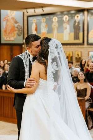Bride and groom share their first kiss at the altar during a traditional church wedding ceremony with guests watching.