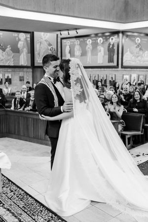 Black and white photo of bride and groom sharing first dance at church wedding ceremony.