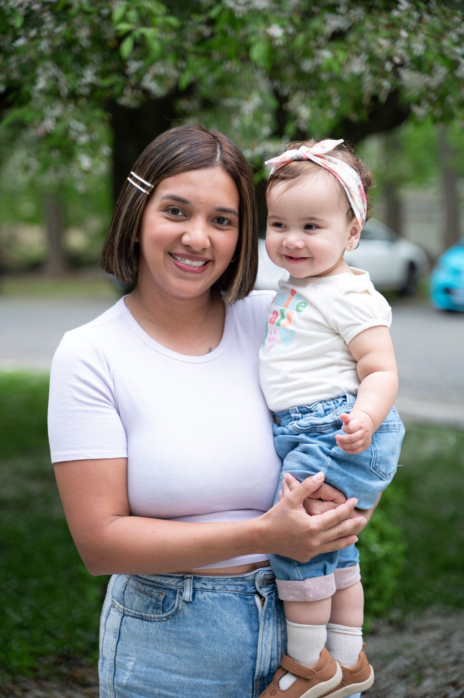 Mother and baby pose together outdoors on a spring day.