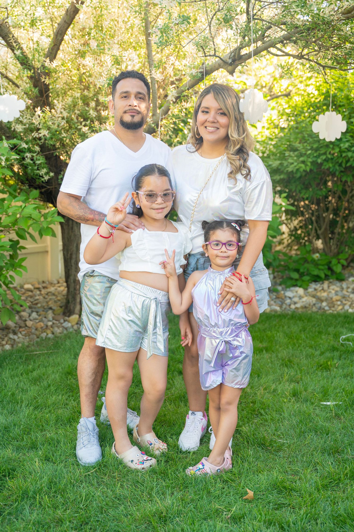 Group wearing coordinated white and tie-dye outfits posing together on green lawn.