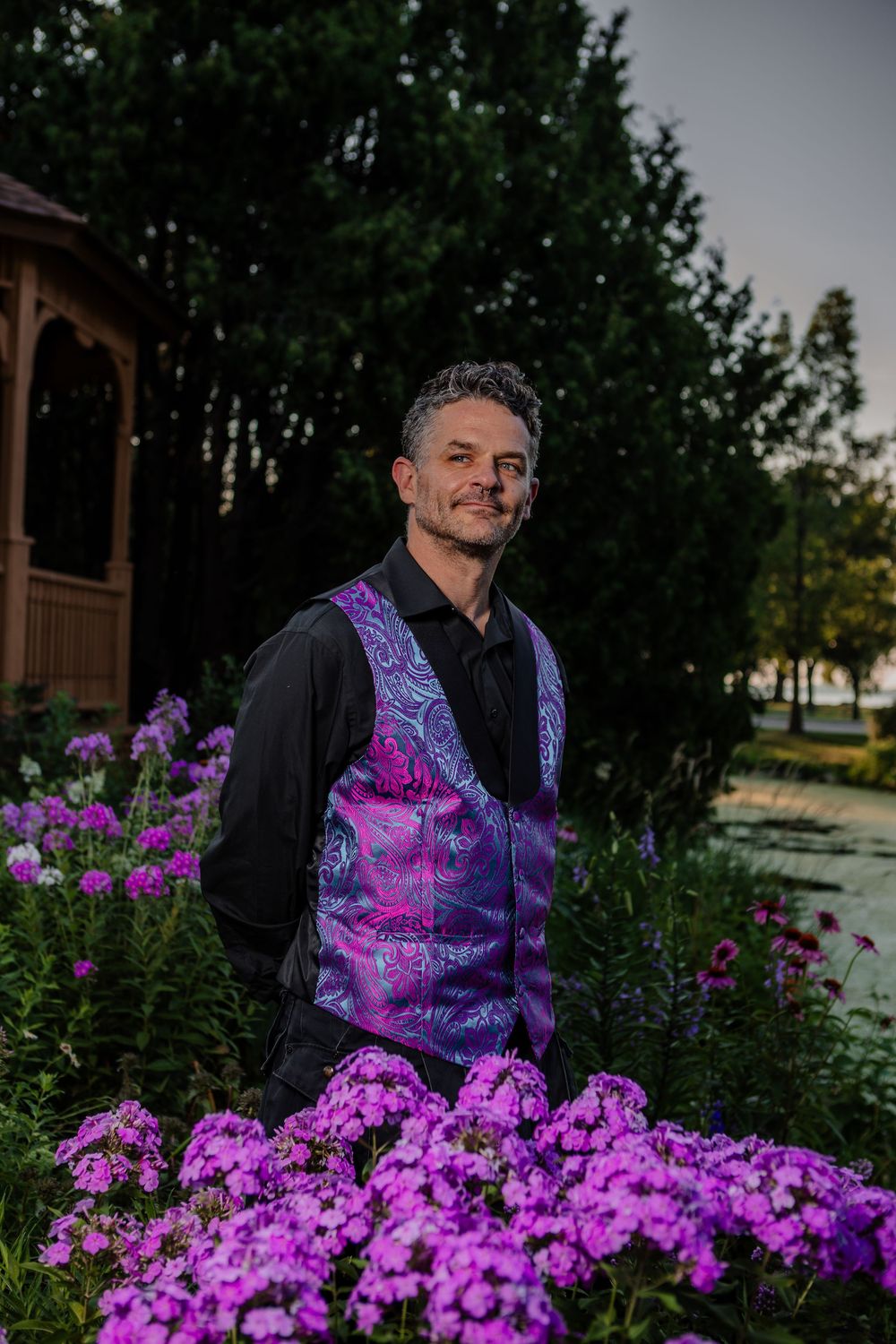 Garden portrait session with vibrant purple flowers in foreground at sunset.
