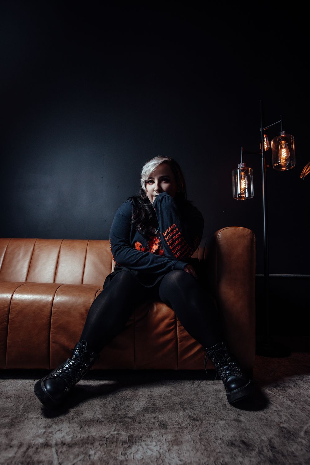 Moody dark photos on a brown leather couch with lantern lighting creating dramatic shadows.