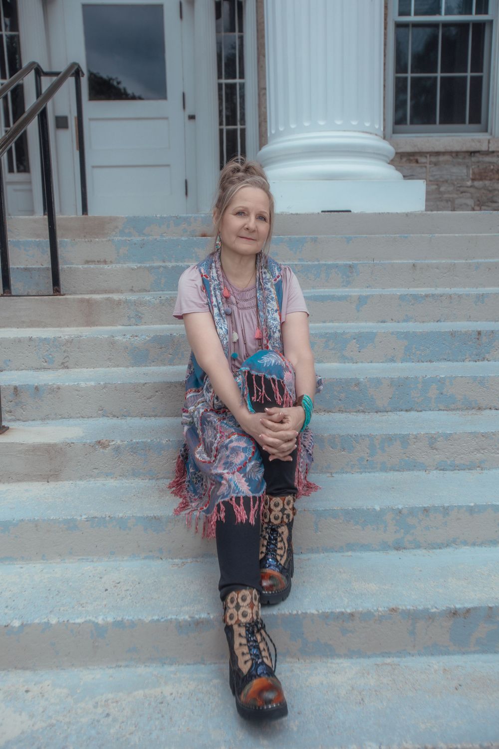 Person sitting on concrete steps wearing colorful patterned clothing.