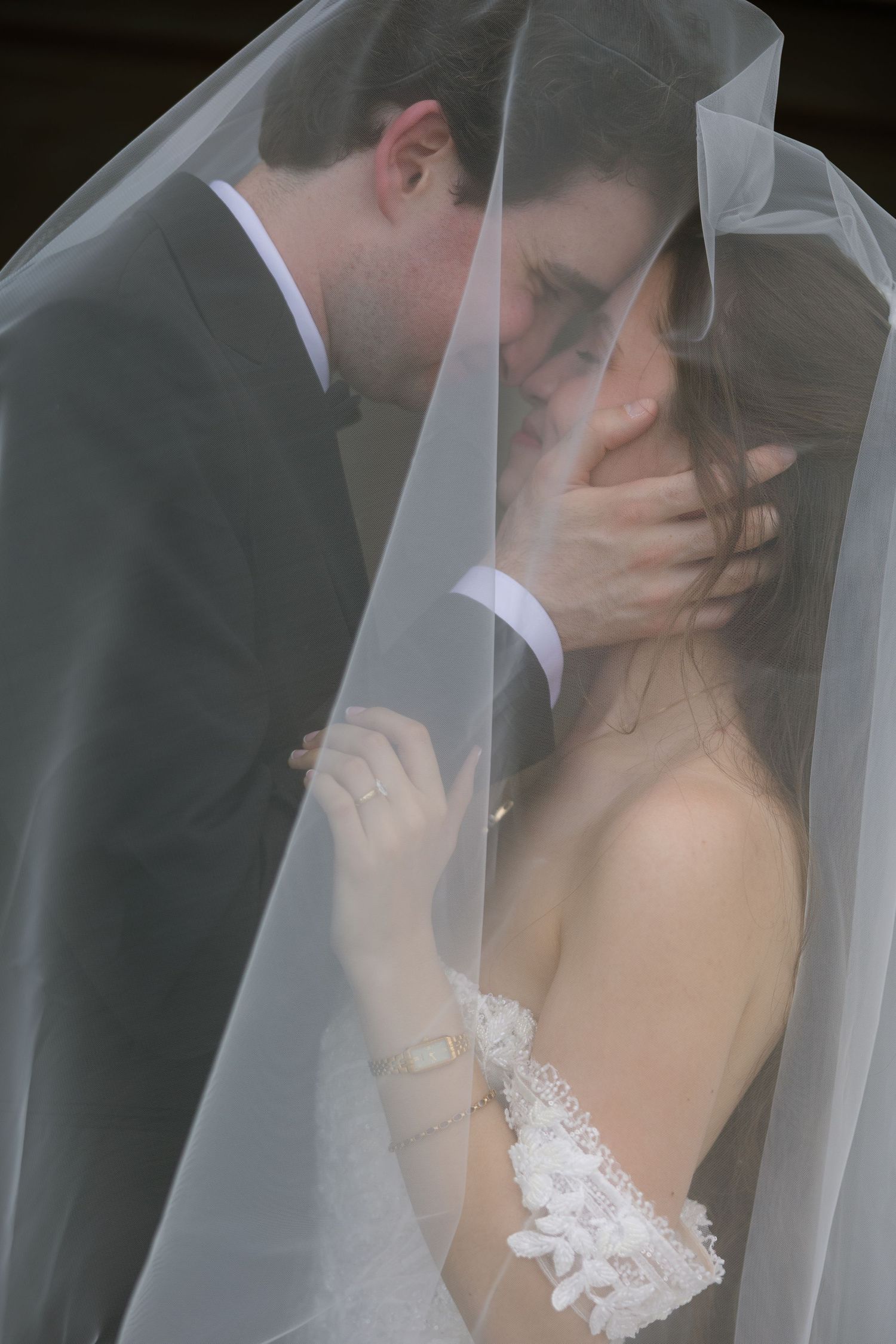 A couple in formal attire ascends a decorated staircase near a waterfront.