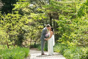 Bride and groom sharing an intimate moment on a garden path surrounded by lush green spring foliage.