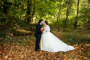 Bride and groom kissing in a forest covered with golden autumn leaves during wedding.