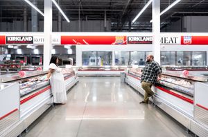Couple sharing a romantic proposal moment in the Kirkland meat department of a Costco warehouse store.