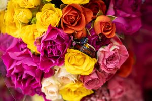 Colorful arrangement of yellow, orange, pink, and magenta roses with an engagement ring nestled inside.