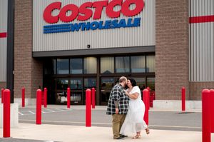 Couple sharing romantic kiss outside Costco Wholesale store entrance.