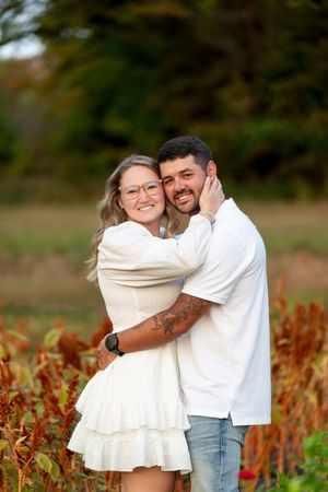Happy newly engaged couple hugging and smiling in a lush autumn garden setting.