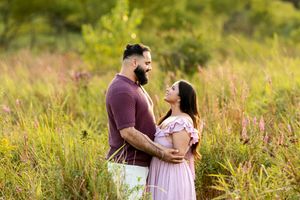 Expecting couple embracing tenderly in a sunlit meadow during a golden hour maternity photo session.