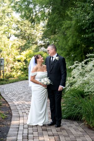 Bride and groom sharing loving glance on brick garden path after wedding.