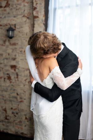Bride and groom share a heartfelt embrace during their first look at rustic venue.