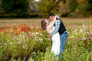 Couple sharing a romantic kiss in a colorful wildflower field during their outdoor engagement photo session.