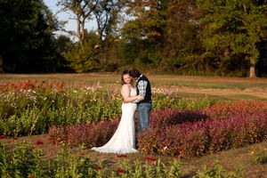 Bride and groom embrace romantically in a vibrant flower garden at golden hour during their wedding.
