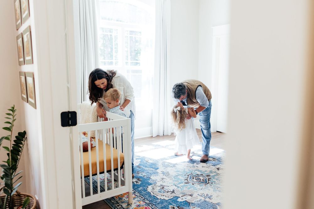 A parent and child work together to assemble furniture in a bright white nursery room.