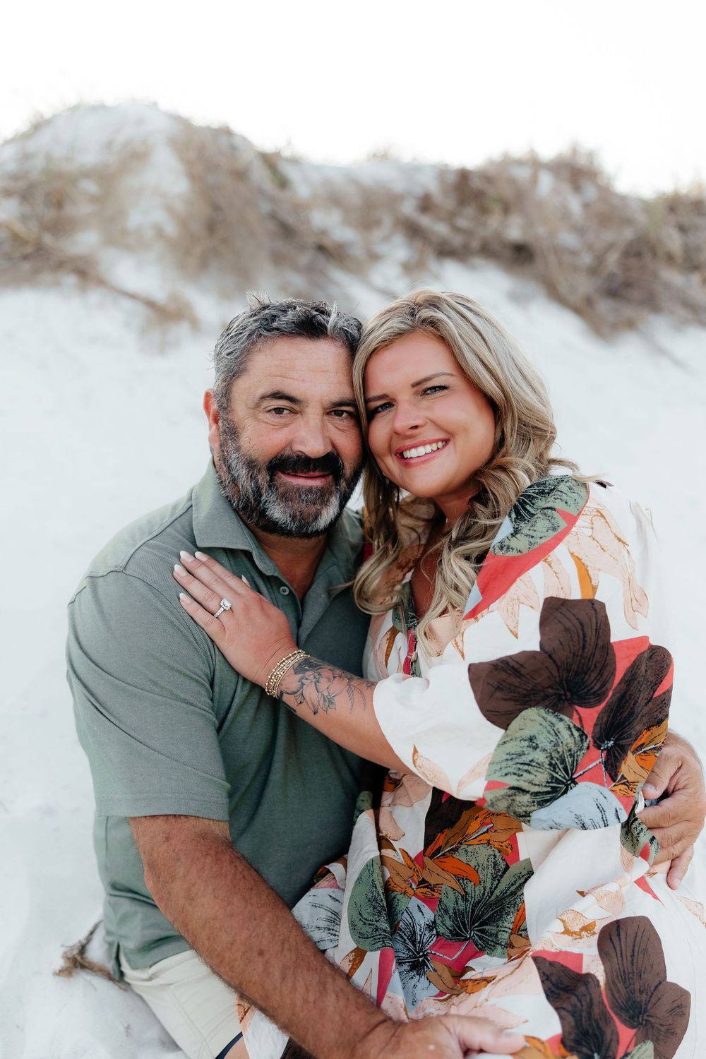 Romantic portrait of couple embracing on white sand dunes at sunset.