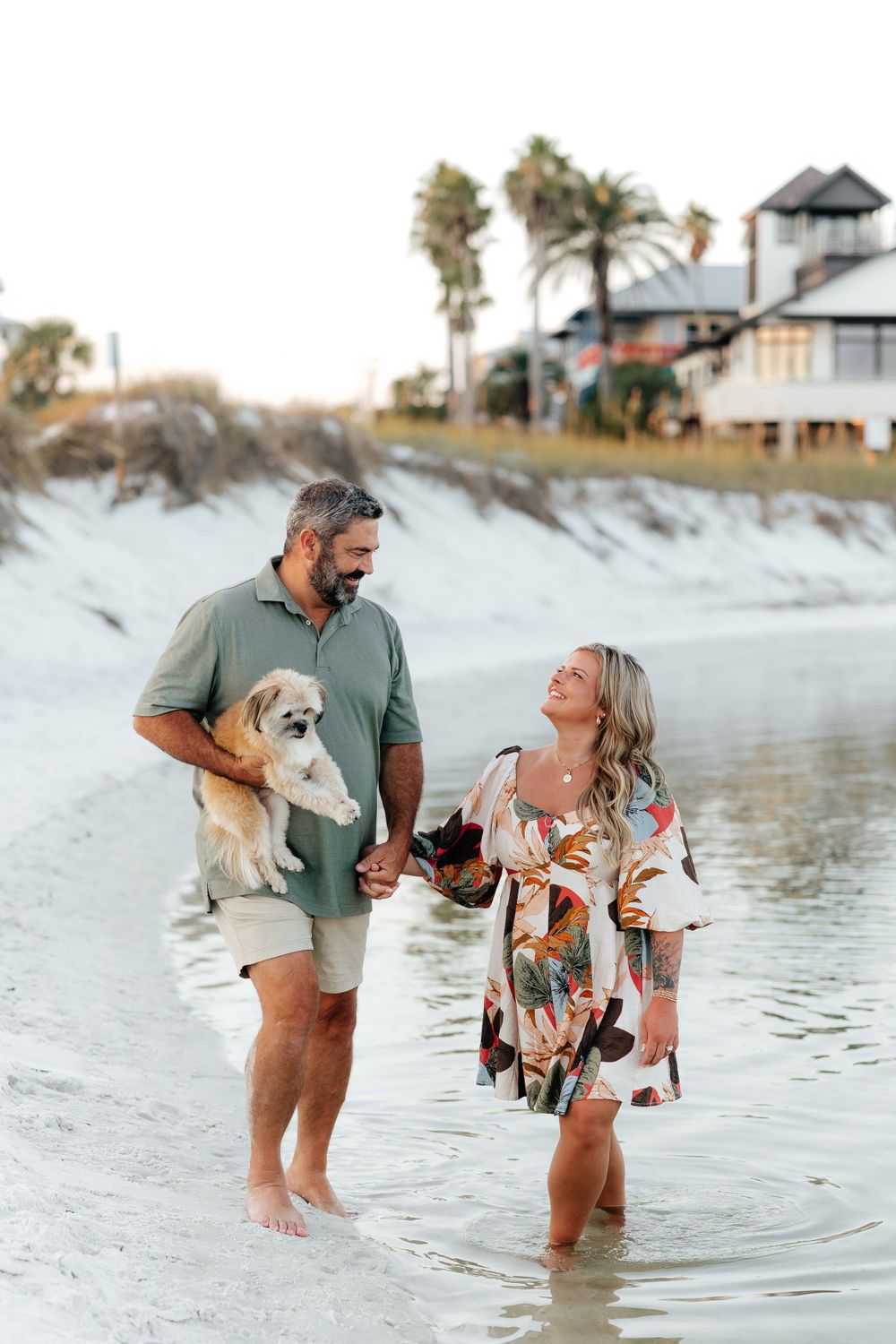 Couple enjoys beach time with their dog while wearing casual summer attire.