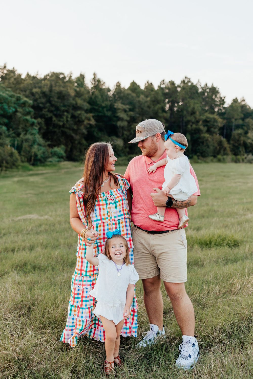 A family poses together in a grassy field wearing coordinated outfits.