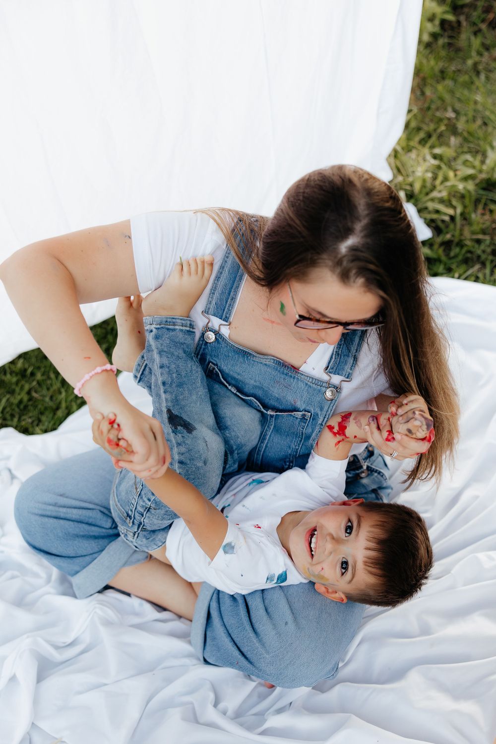 Playful art time with paint supplies on white blanket outdoors.