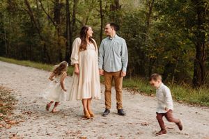 Family enjoying a walk together on a winding autumn trail through a wooded forest setting.