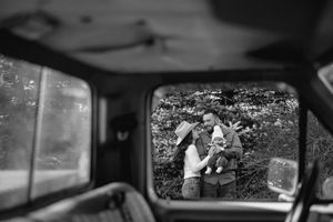 Black and white view through car window showing loving moment in nature captured as tender silhouettes.