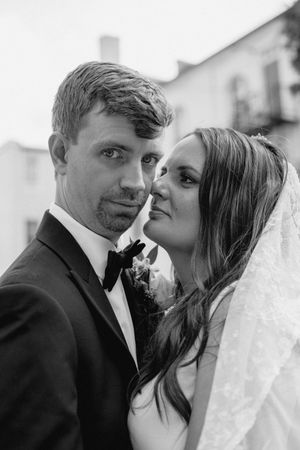 Black and white portrait of a newlywed couple in elegant wedding attire sharing an intimate moment together.