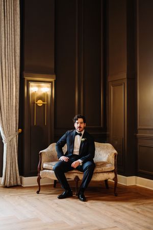 Elegant formal attire in a classic setting with rich wood paneling and warm sconce lighting in an upscale interior.