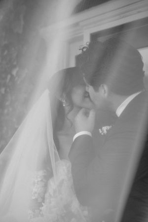 A tender black and white wedding moment captured through a dreamy, soft-focus veil effect during the ceremony.